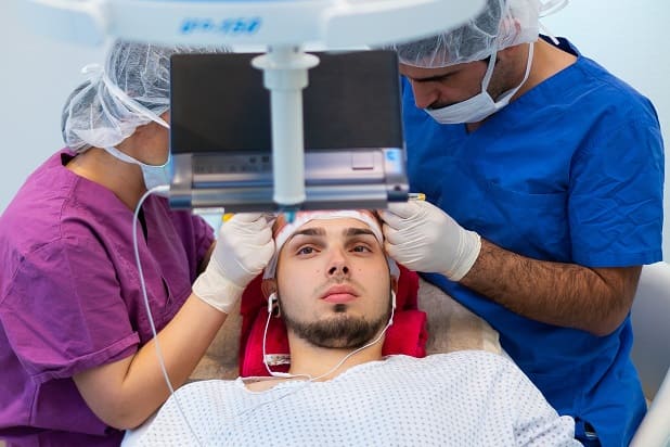 FUE Haartransplantation - Patient schaut Fernsehr während der Behandlung