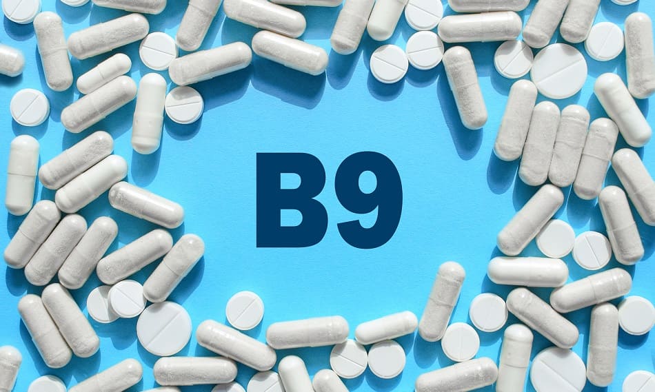 Vitamin B9 kann für gesunden Haarwuchs sorgen Vitamin B9 Text umgeben von diversen Tabletten und Kapseln