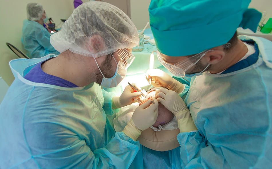 Zwei Ärzte führen an einem Patienten eine Haartransplantation durch