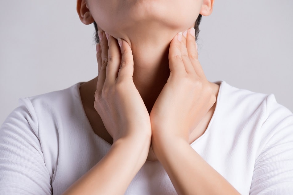 Frau mit Schilddrüsenproblemen fässt sich an den Hals