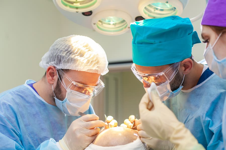Arzt bei der Haartransplantation an einem Patienten in der OP-Saal