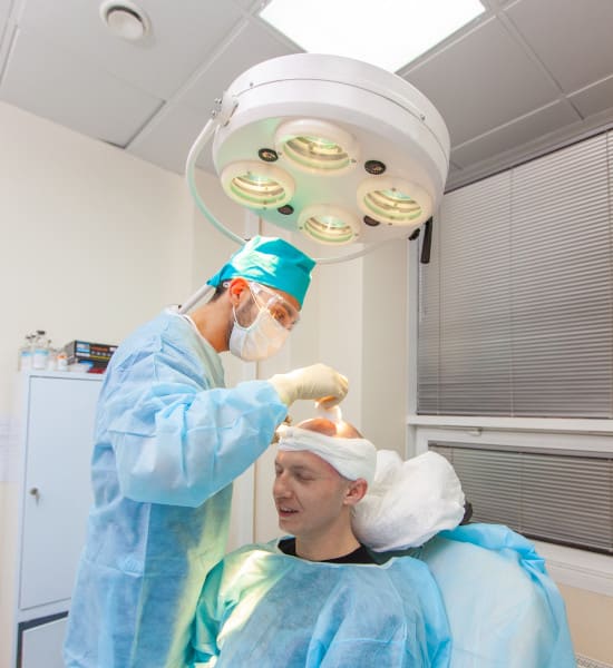 haartransplantation-behandlung-am-patienten Arzt führt Haartransplantation am Patienten durch.