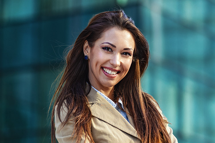 Lächelnde Frau vor Bürogebäude mit vollen Haaren