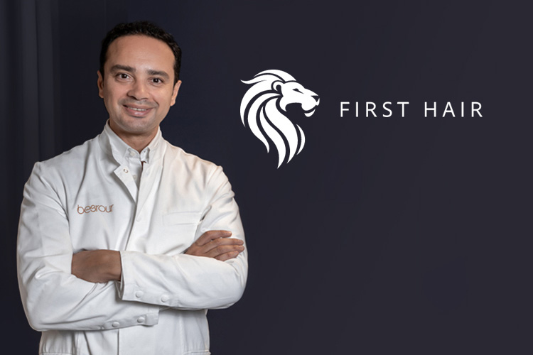 Dr Besrour lächelt in die Kamera neben dem First Hair Logo